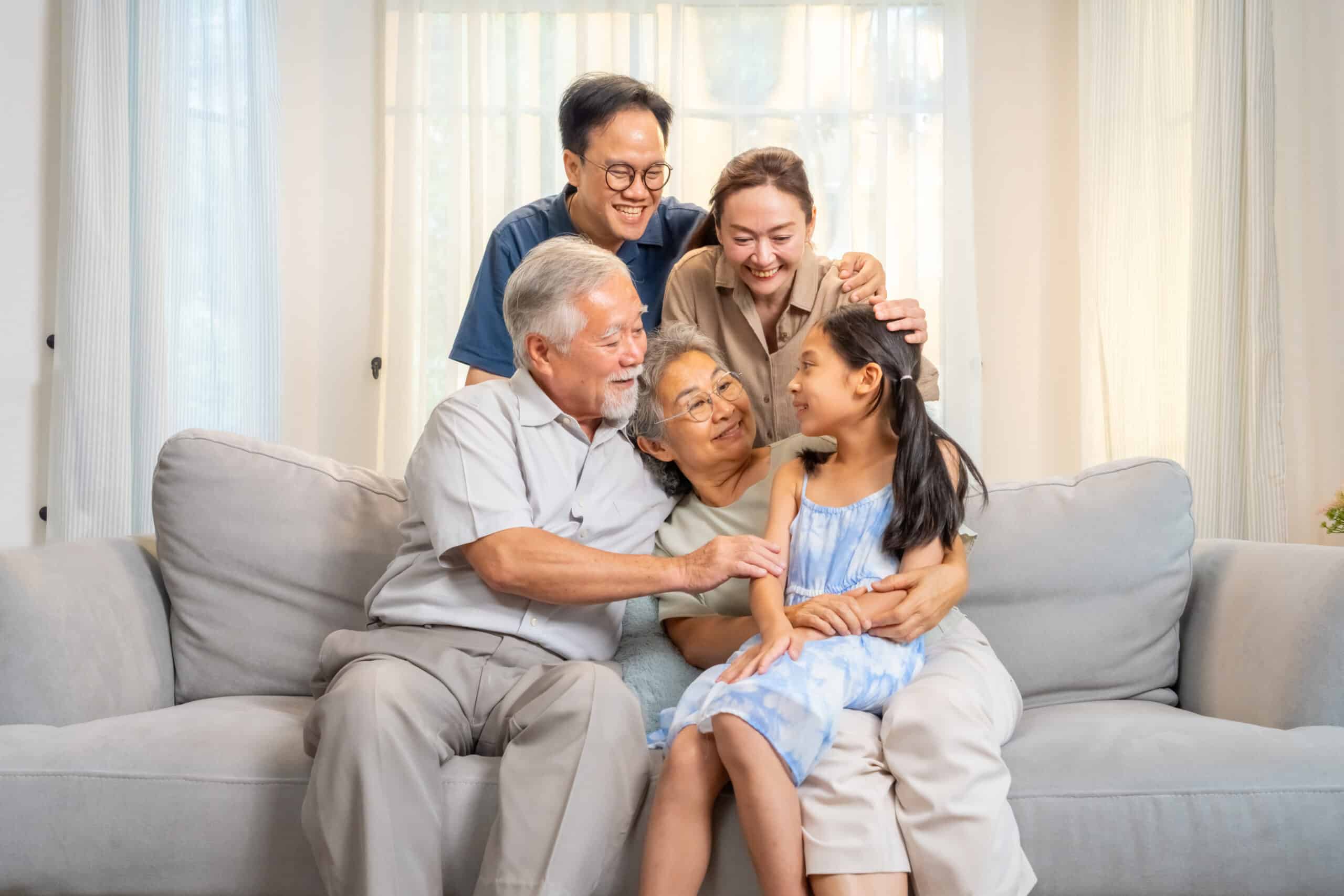 A family sits happily together on a couch, sharing smiles and affection.
