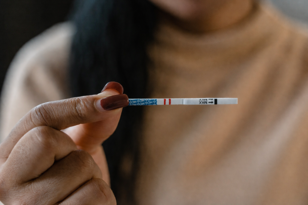 Hand holding a pregnancy test strip showing two lines.