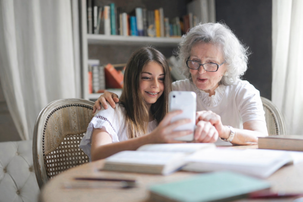 Older and younger person sitting together, looking at a smartphone in a study room.
