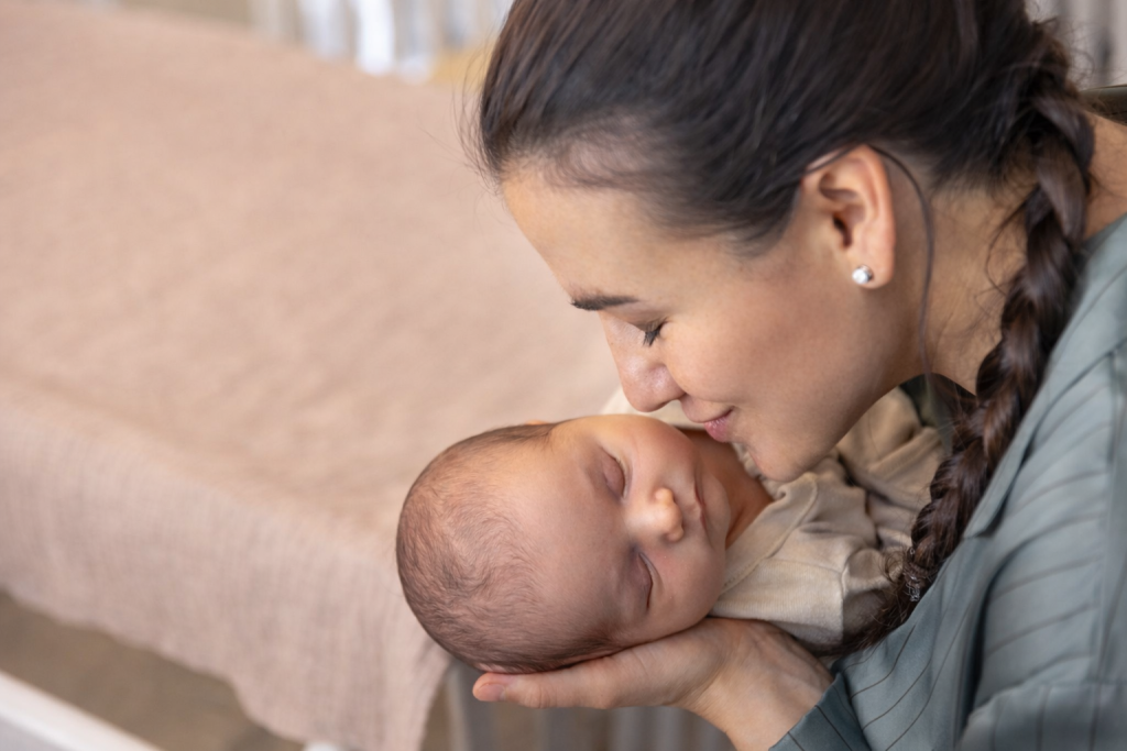 Adult gently holding a sleeping baby in a warm, intimate moment.